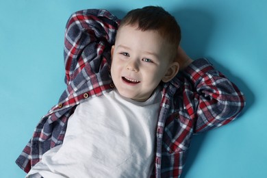Photo of Cute little boy on light blue background, top view