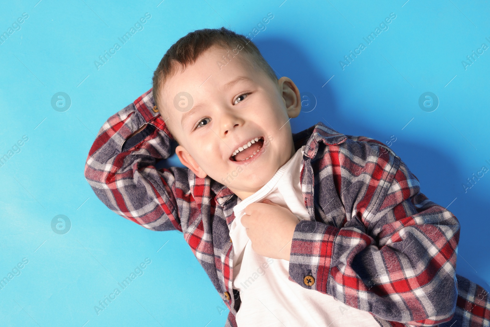 Cute little boy on light blue background, top view Photo of Cute little boy on light blue background, top view