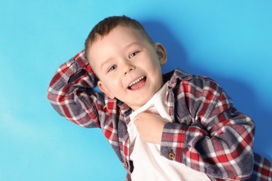 Photo of Cute little boy on light blue background, top view