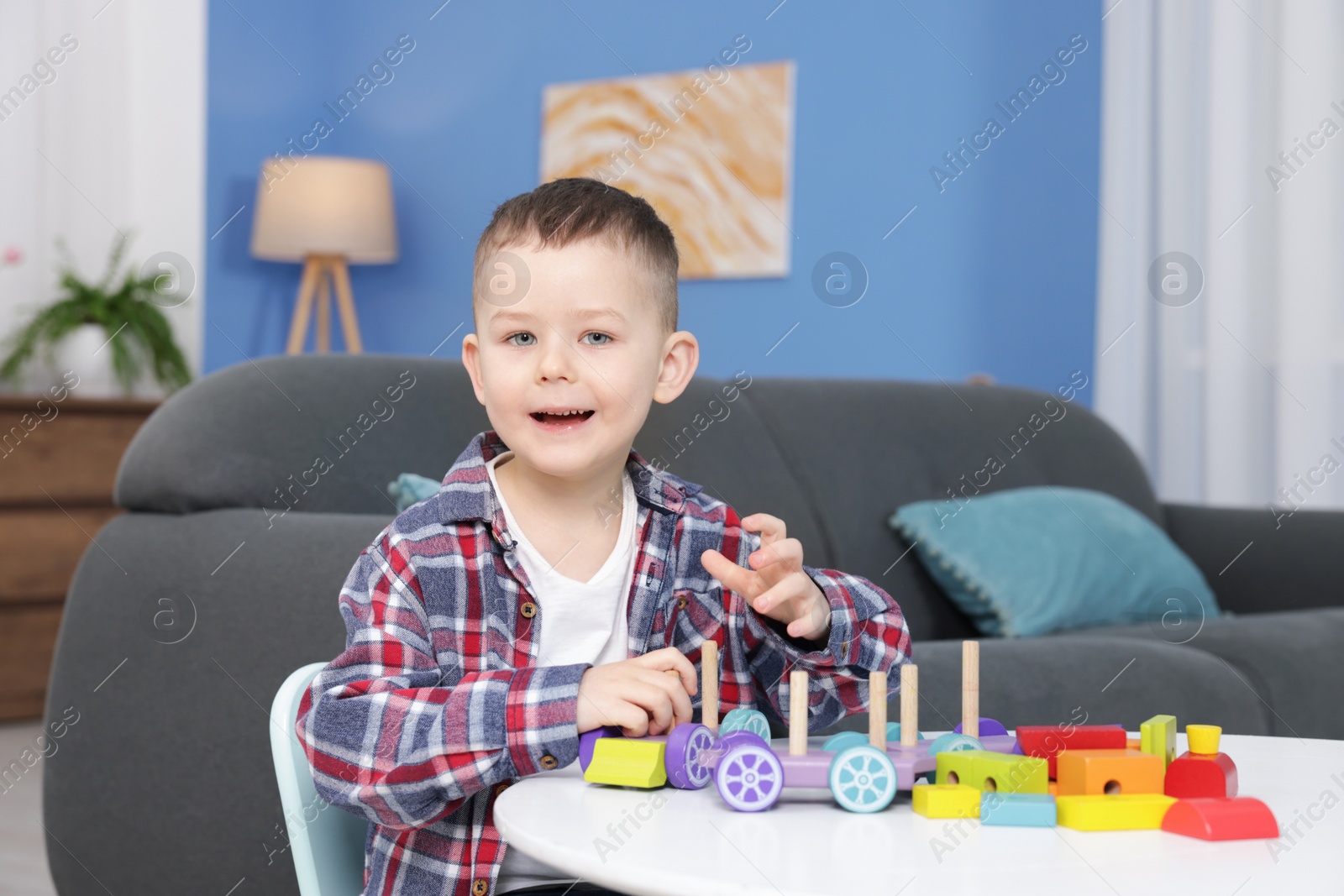 Cute little boy playing with train toy at table indoors Photo of Cute little boy playing with train toy at table indoors