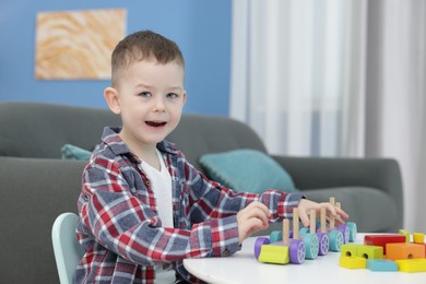 Photo of Cute little boy playing with train toy at table indoors