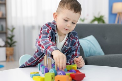 Photo of Cute little boy playing with train toy at table indoors