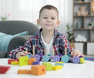 Photo of Cute little boy playing with train toy at table indoors