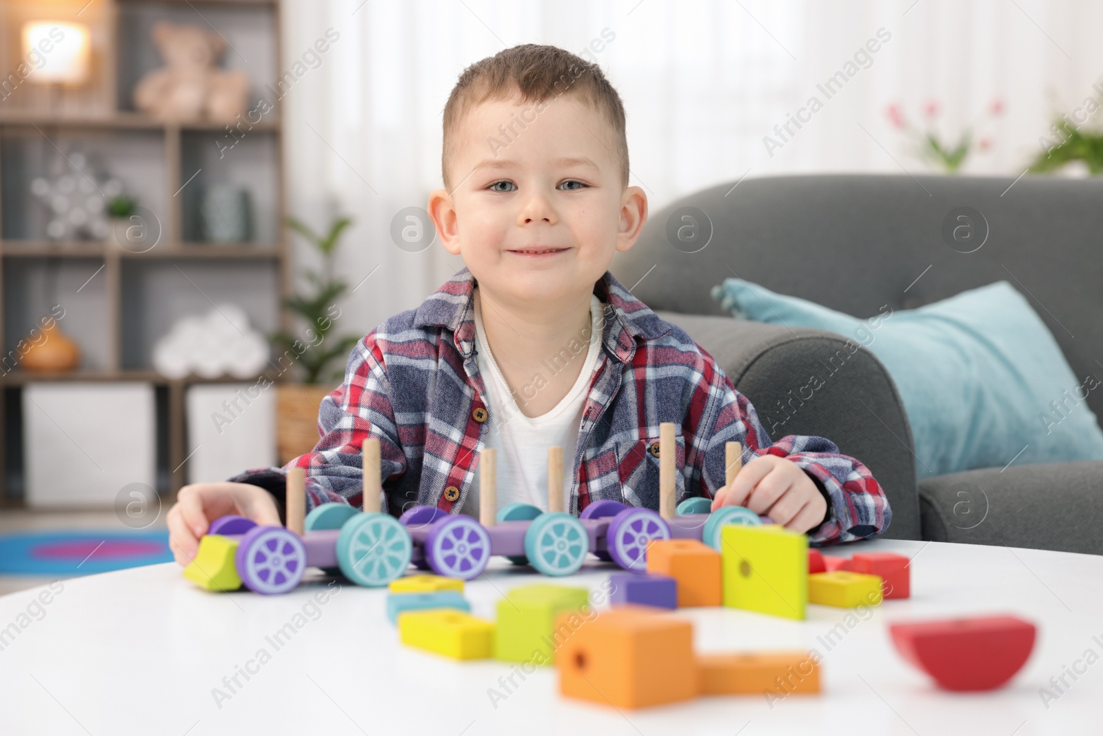 Cute little boy playing with train toy at table indoors Photo of Cute little boy playing with train toy at table indoors