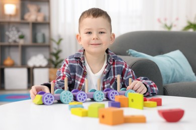 Photo of Cute little boy playing with train toy at table indoors