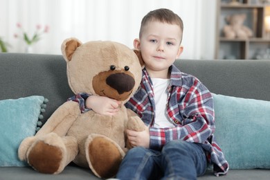 Photo of Cute little boy with toy bear at home