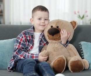 Photo of Cute little boy with toy bear at home