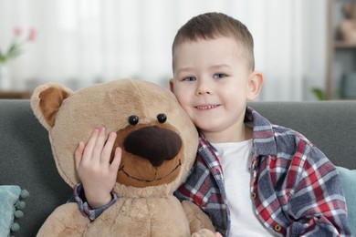 Photo of Cute little boy with toy bear at home