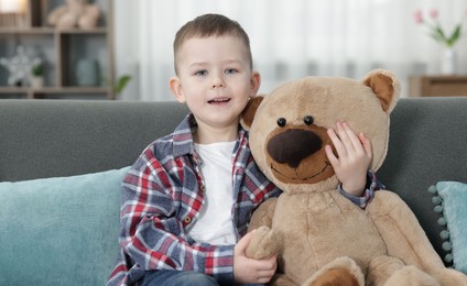 Photo of Cute little boy with toy bear at home