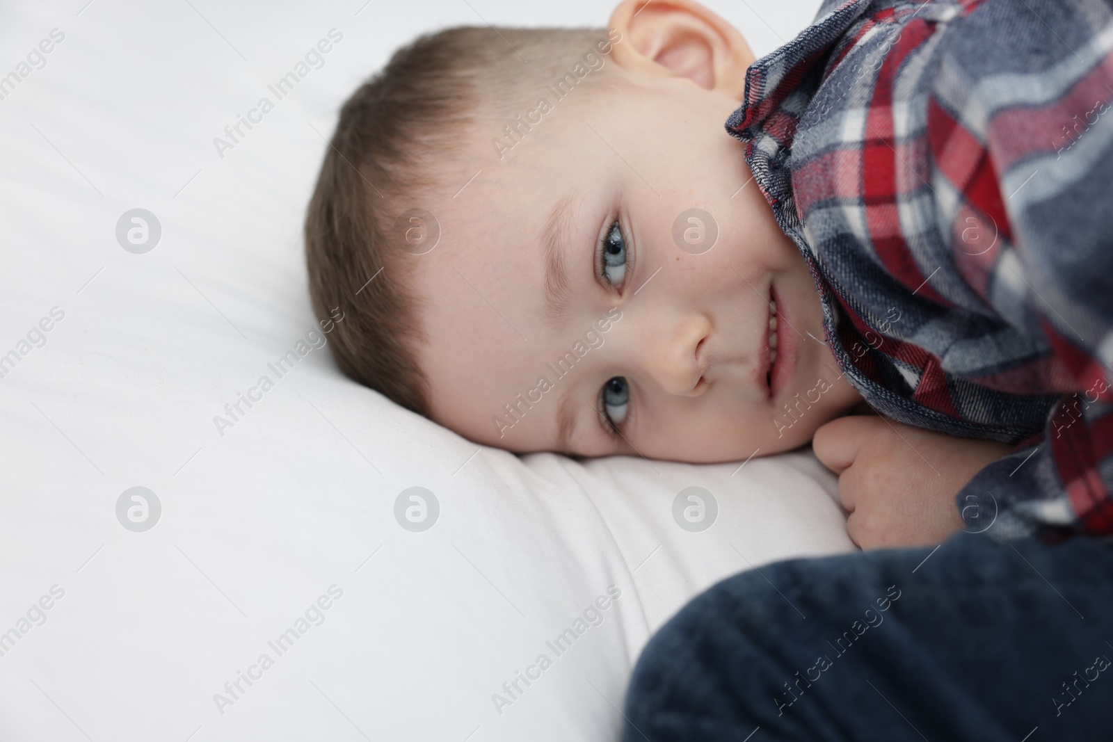 Cute little boy lying on bed at home Photo of Cute little boy lying on bed at home