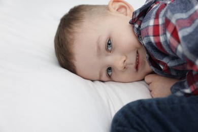 Photo of Cute little boy lying on bed at home