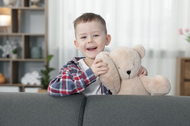 Photo of Cute little boy with toy bear at home
