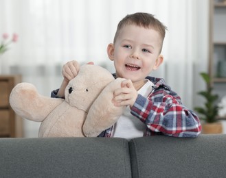 Photo of Cute little boy with toy bear at home