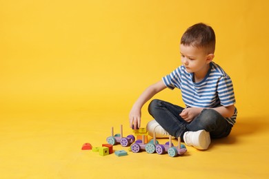 Photo of Cute little boy playing on yellow background, space for text