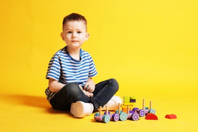 Photo of Cute little boy with toys on yellow background