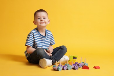 Photo of Cute little boy with toys on yellow background