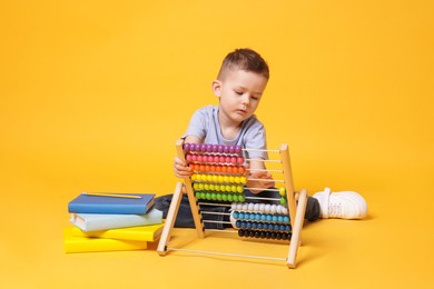 Photo of Cute little boy playing with wooden abacus on yellow background
