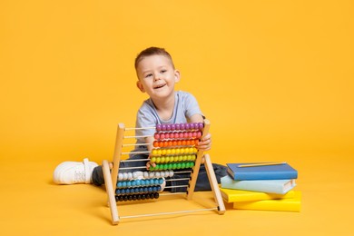 Photo of Cute little boy playing with wooden abacus on yellow background