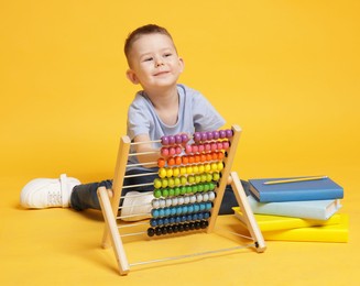 Photo of Cute little boy playing with wooden abacus on yellow background