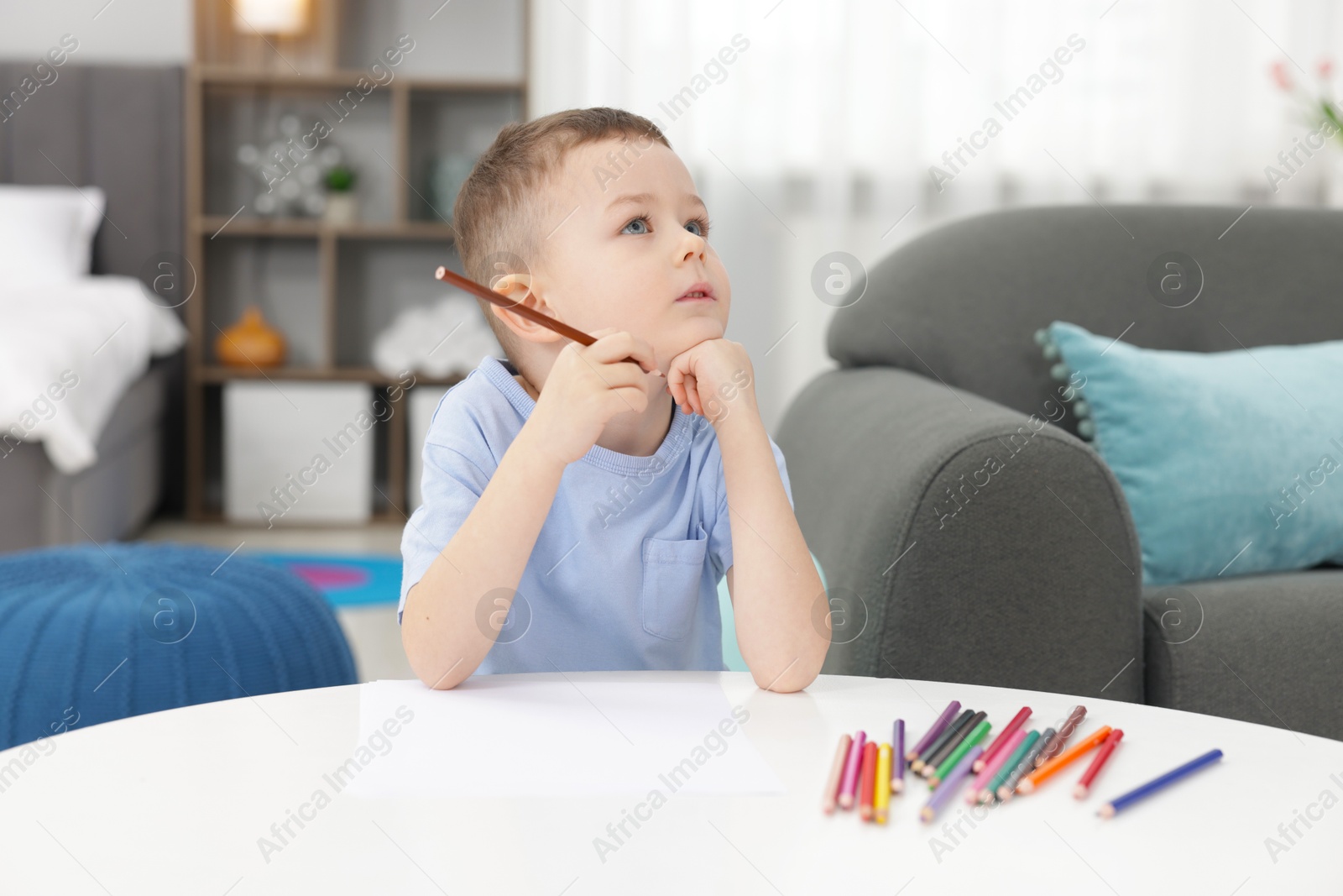 Cute little boy with brown pencil at table indoors Photo of Cute little boy with brown pencil at table indoors