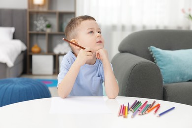 Photo of Cute little boy with brown pencil at table indoors
