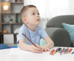 Photo of Cute little boy drawing at table indoors