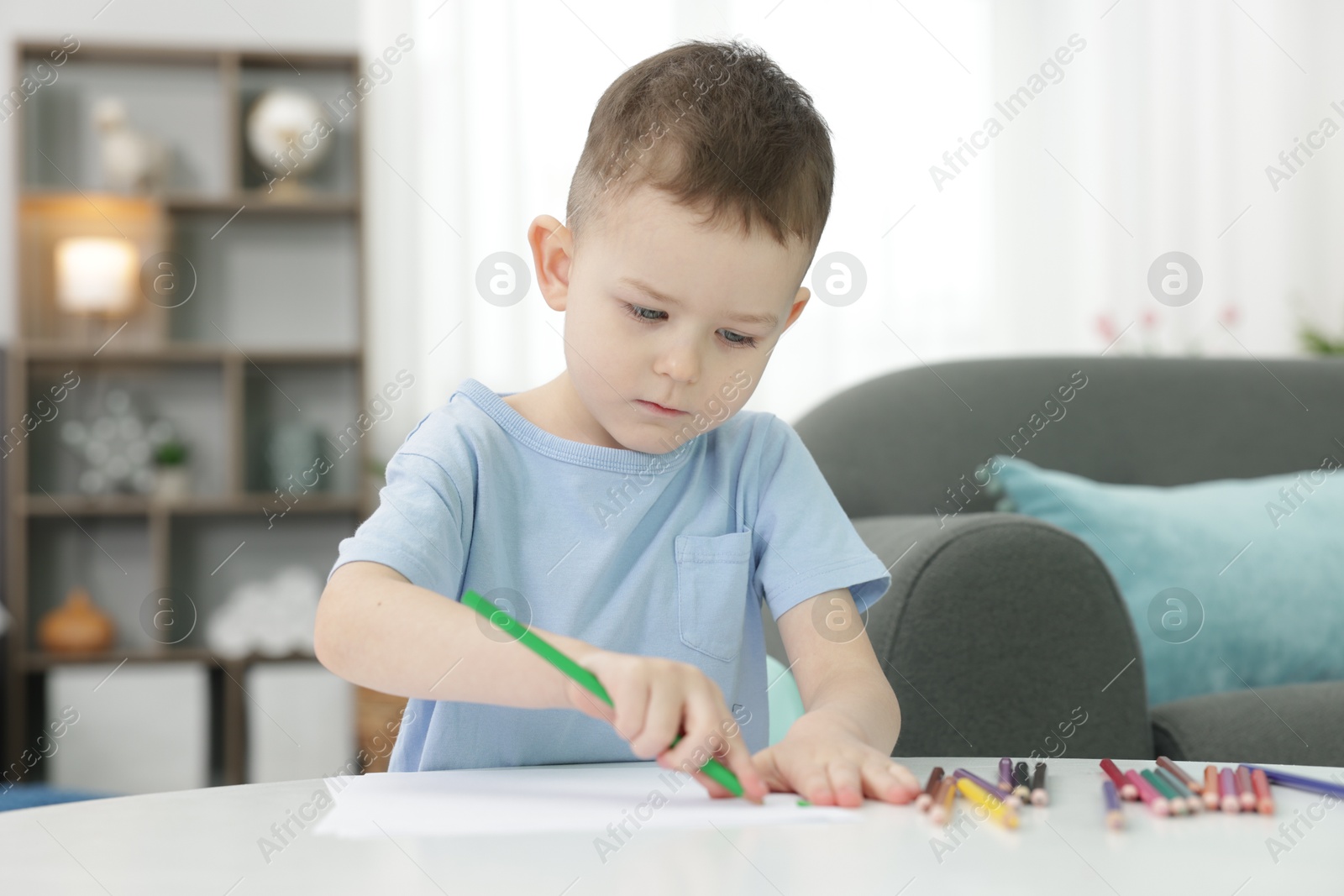 Cute little boy drawing at table indoors Photo of Cute little boy drawing at table indoors