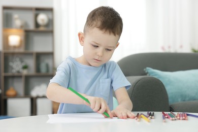 Photo of Cute little boy drawing at table indoors