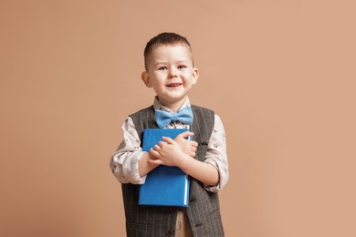Photo of Cute little boy with book on beige background