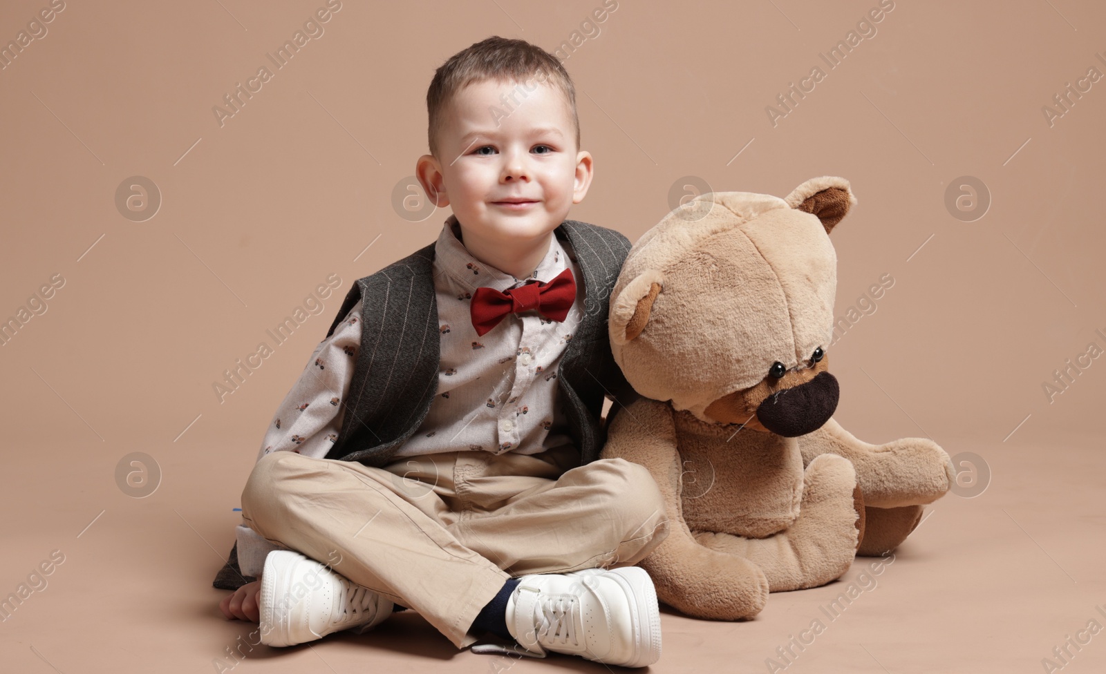 Cute little boy with toy bear on beige background Photo of Cute little boy with toy bear on beige background