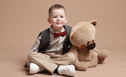 Photo of Cute little boy with toy bear on beige background