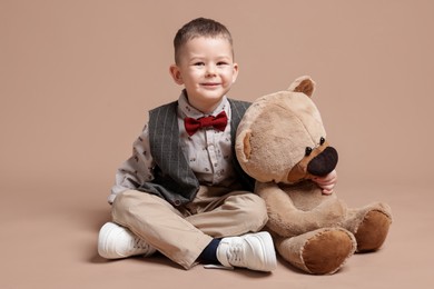 Photo of Cute little boy with toy bear on beige background