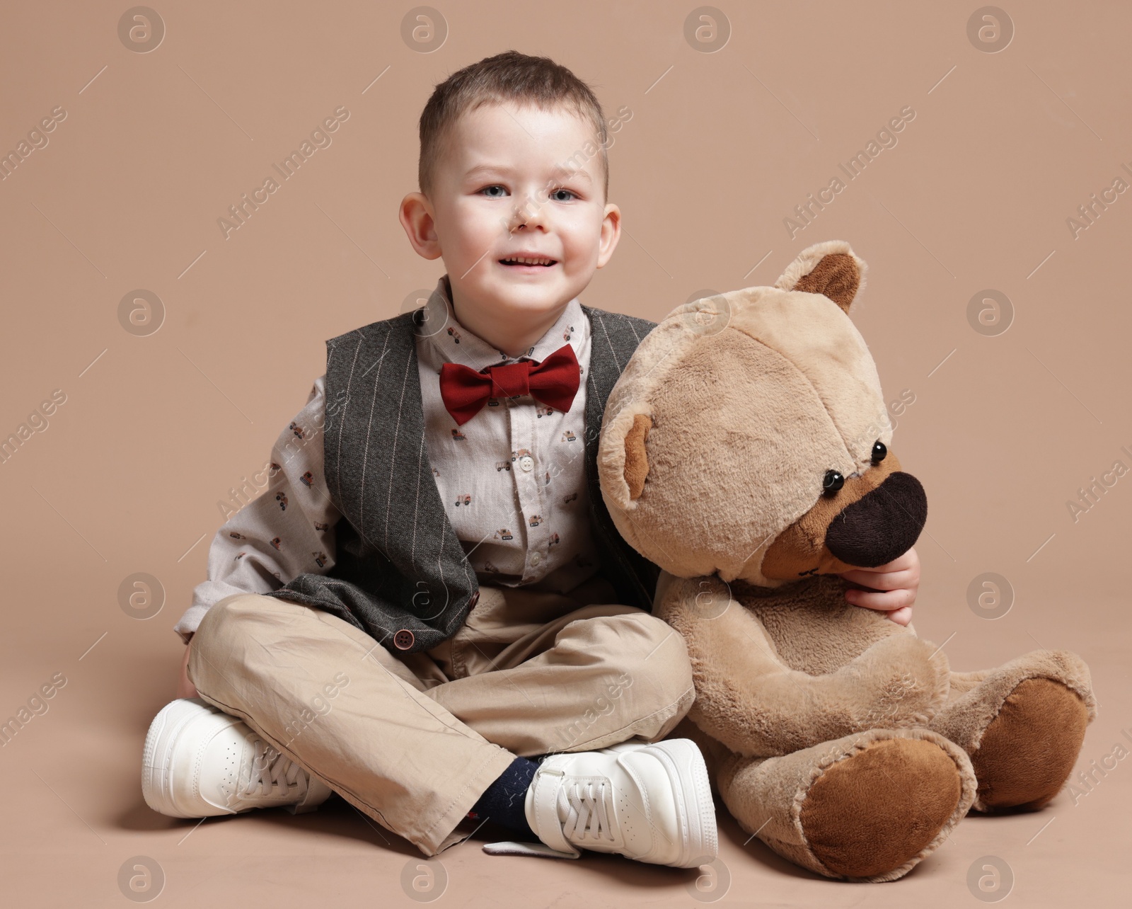 Cute little boy with toy bear on beige background Photo of Cute little boy with toy bear on beige background