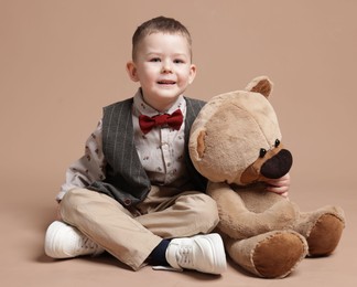 Photo of Cute little boy with toy bear on beige background