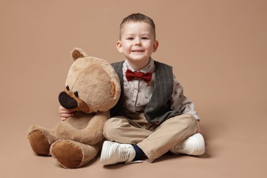 Photo of Cute little boy with toy bear on beige background
