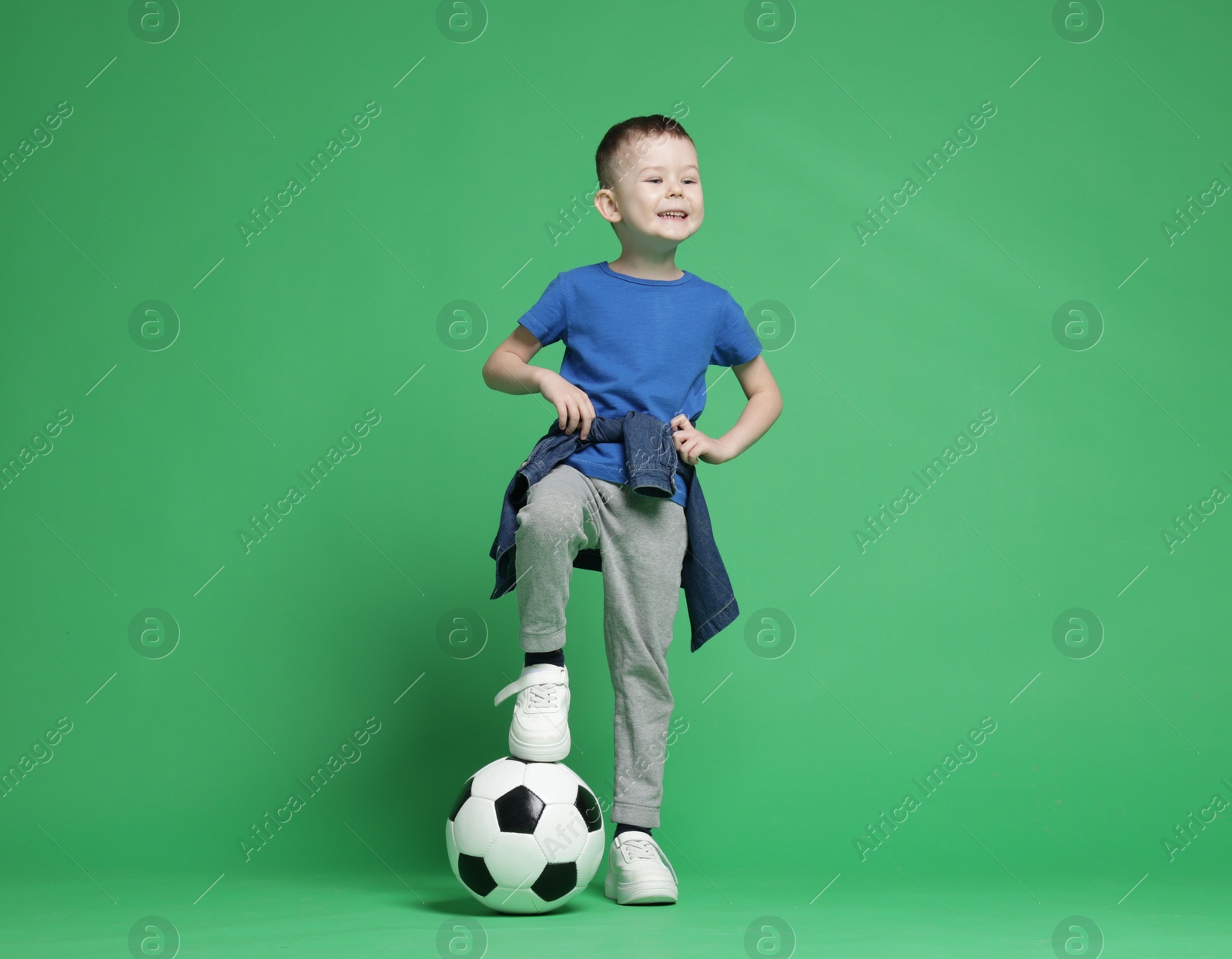 Cute little boy with soccer ball on green background Photo of Cute little boy with soccer ball on green background