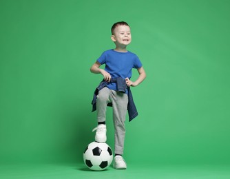 Photo of Cute little boy with soccer ball on green background