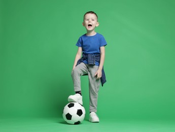 Photo of Cute little boy with soccer ball on green background