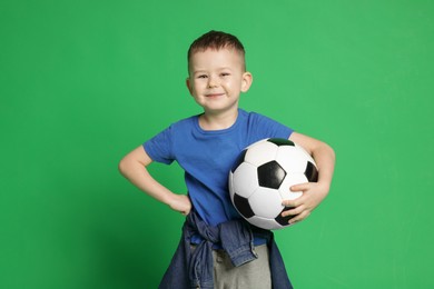 Photo of Cute little boy with soccer ball on green background