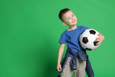 Photo of Cute little boy with soccer ball on green background, space for text