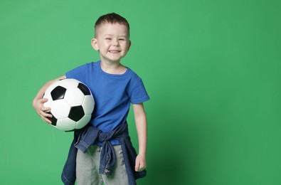 Photo of Cute little boy with soccer ball on green background, space for text