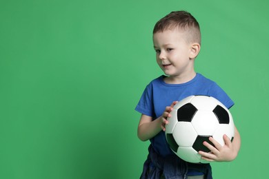 Photo of Cute little boy with soccer ball on green background, space for text