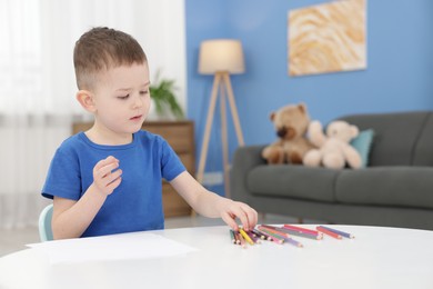 Photo of Cute little boy with colorful pencils at table indoors
