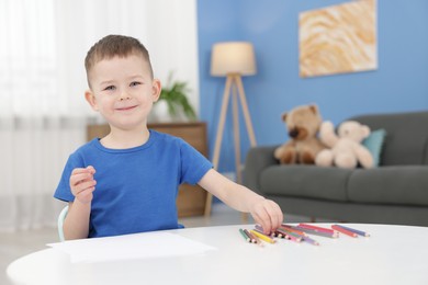 Photo of Cute little boy with colorful pencils at table indoors