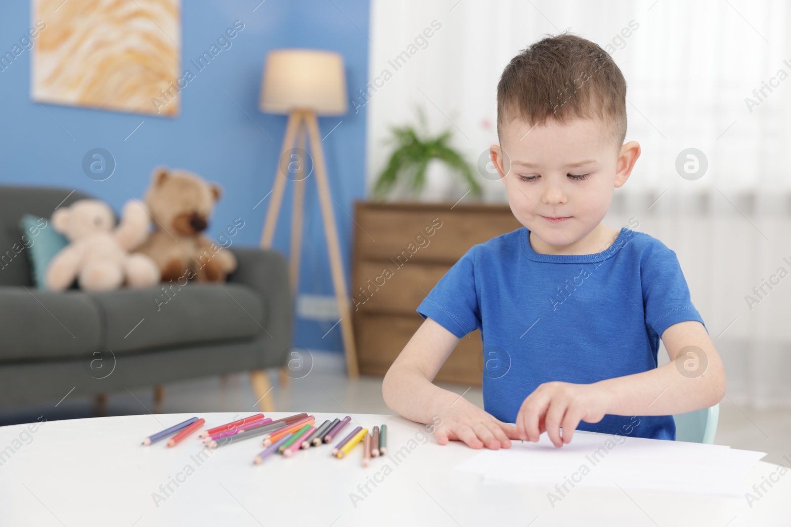 Cute little boy with colorful pencils at table indoors Photo of Cute little boy with colorful pencils at table indoors