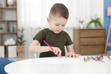 Photo of Cute little boy with drawing at table indoors