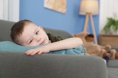 Photo of Cute little boy lying on sofa at home