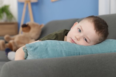 Photo of Cute little boy lying on sofa at home