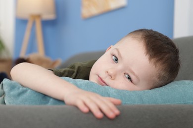 Photo of Cute little boy lying on sofa at home