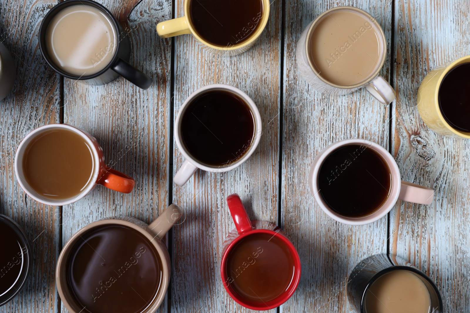 Different cups with aromatic coffee drinks on color wooden table, flat lay Photo of Different cups with aromatic coffee drinks on color wooden table, flat lay